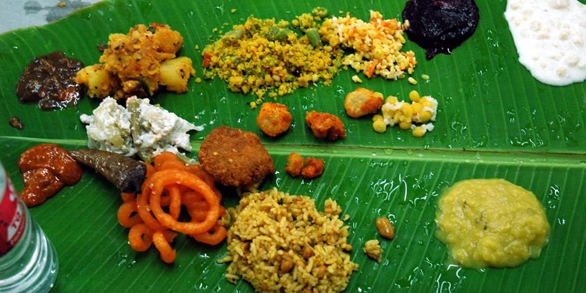 Traditional Assamese folk cuisine served on a banana leaf, showcasing diverse dishes.