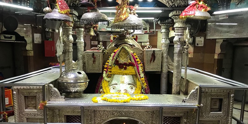 A picture of a temple's interior with the idol of Goddess Kalka in front, dressed with garlands