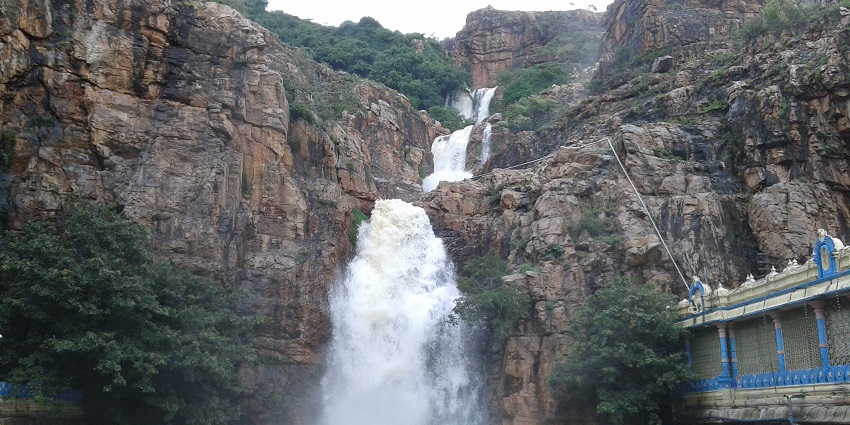 Scenic view of Kapila Theertham waterfalls in Tirupati, surrounded by lush greenery and rocks.