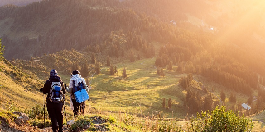 View of magnificent sun hues reflecting upon the verdant fields with tourists trekking amidst