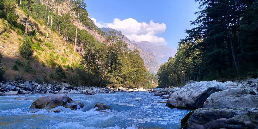 A picture of a river flowing in between two mountains on a sunny day