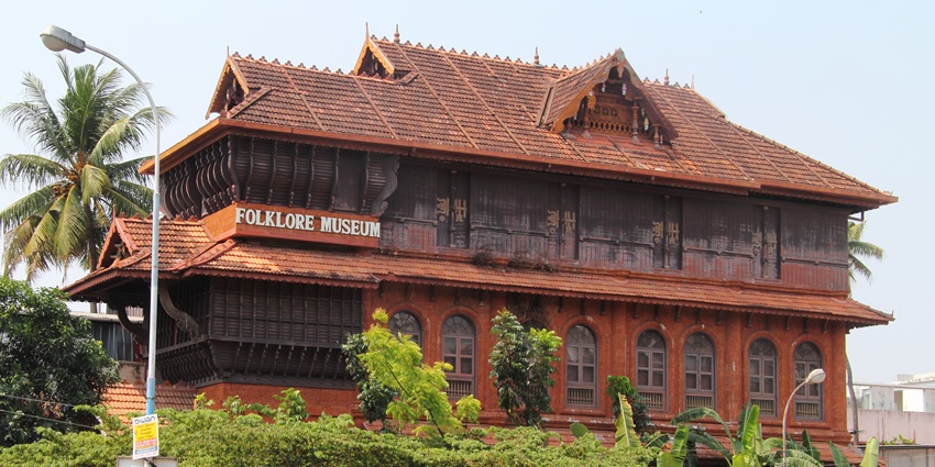 A picture of the Kerala Folklore Museum from the parking area with cars parked