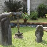 Artefacts placed in a museum's garden with green grass and trees, on a bright, sunny day