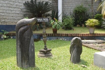 Artefacts placed in a museum's garden with green grass and trees, on a bright, sunny day