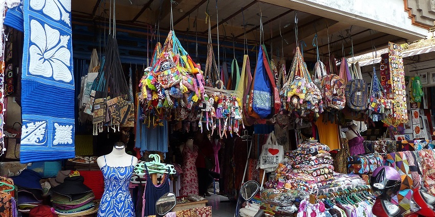 A picture of a cloth shop in a Bali market with various articles hanging for display