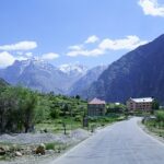 A breathtaking view of a valley covered in lush greenery with snow-covered mountains.