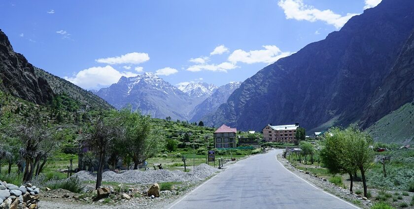 A breathtaking view of a valley covered in lush greenery with snow-covered mountains.