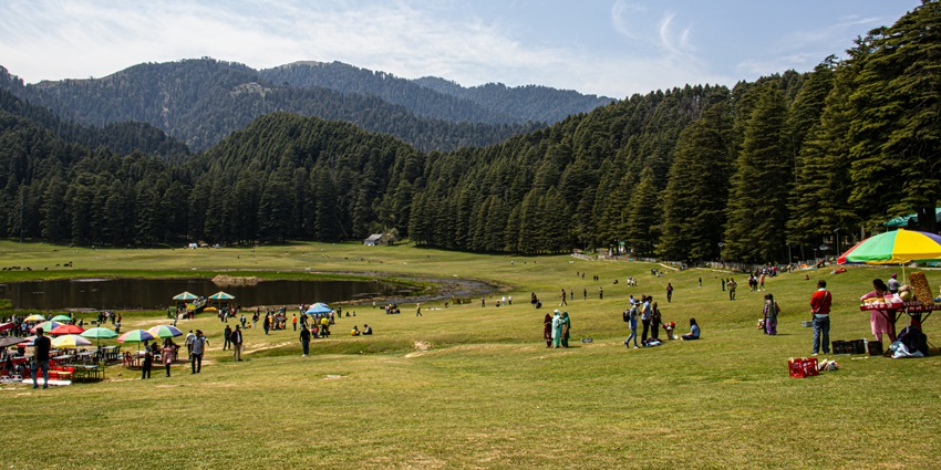 A stunning view of Khajjiar featuring lush green manicured lawns and dense forests.