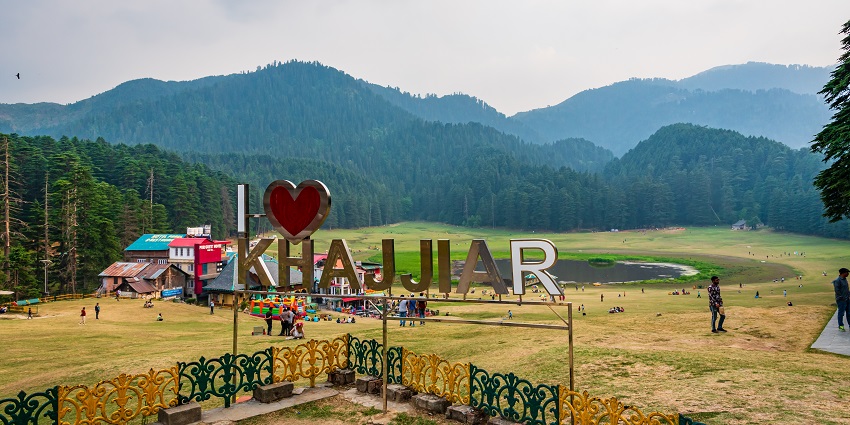 Panoramic view of Khajjiar, India, showcasing lush green meadows and mountains.