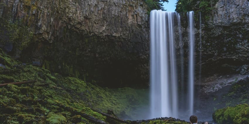 A person stands in awe before a majestic waterfall, capturing the beauty of nature.