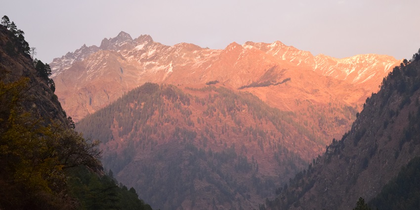 A picture of the majestic mountains in Manikaran during sunrise, under a cover of orange hues