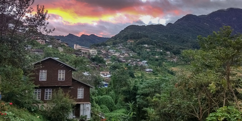 Khonoma Village at dawn with mist-covered hills and traditional Naga houses in soft light.