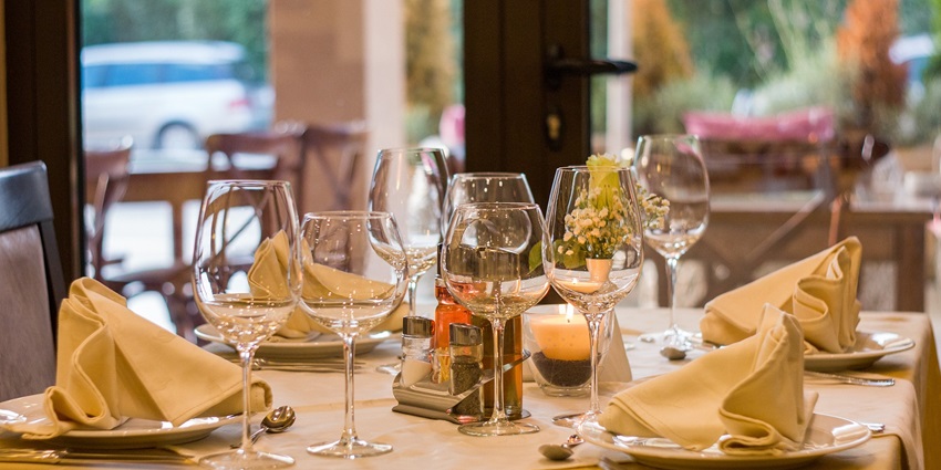 A picture of a restaurant setting with cutlery placed on a table along with the menu