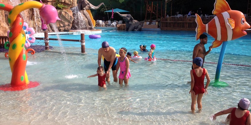 Kids in a waterpark having fun on water slides, playing in splash zones.
