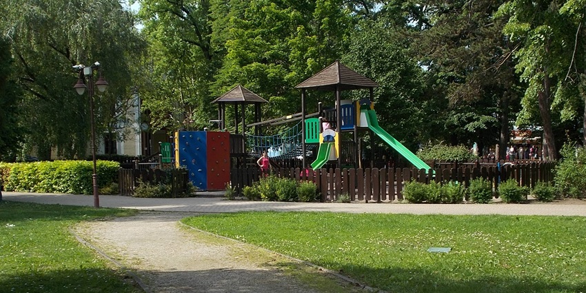 Playground in a park, with kids enjoying swings, slides, and other fun activities.