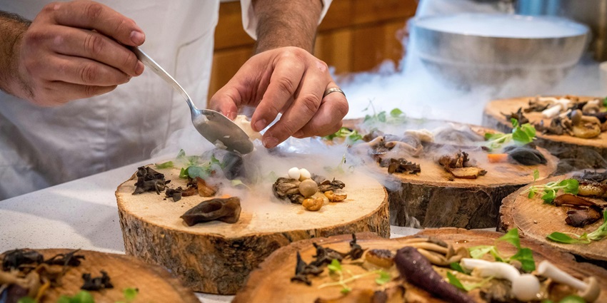 A picture of chefs preparing a dish at a restaurant kitchen