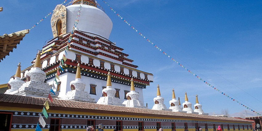 A picture of a scenic monastery with a huge Gompha and yellow walls