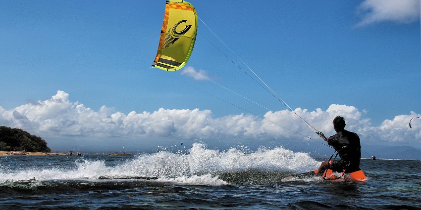 One of the best adventure sports in Bali where a person is tied to a kite for surfing in sea
