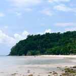 A scenic view of the sandy shores and shimmering waters of Koh Chang Beach, Thailand.