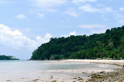 A scenic view of the sandy shores and shimmering waters of Koh Chang Beach, Thailand.