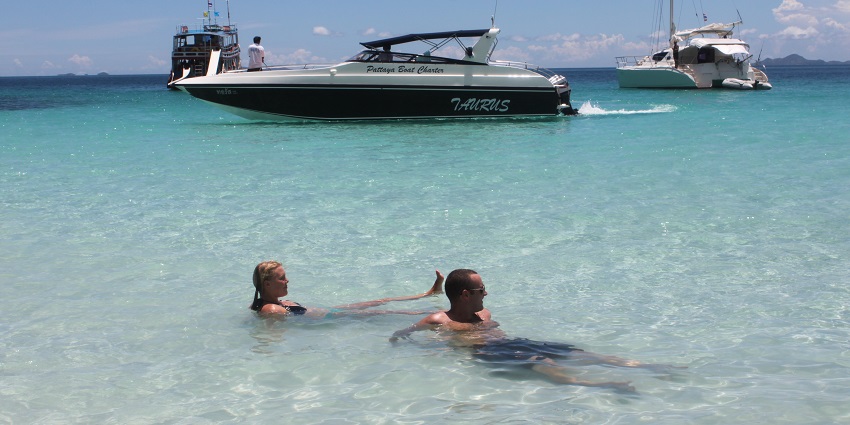 People enjoying on a beach with a boat in the background