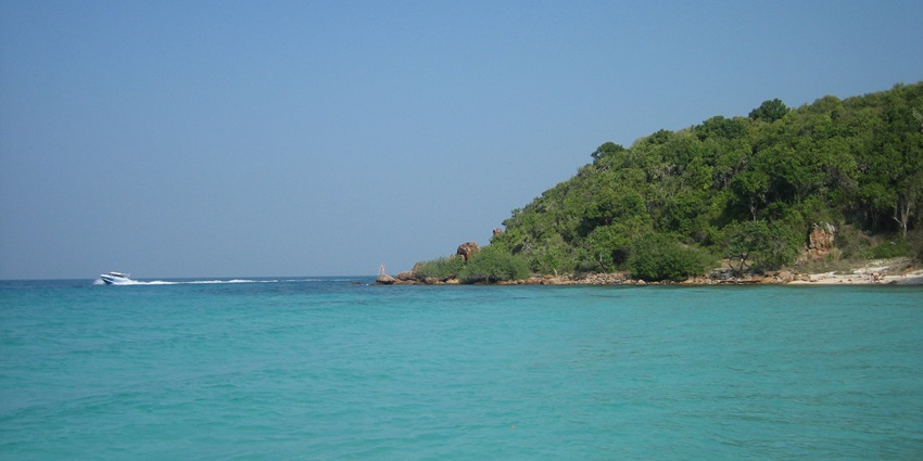 A distant picture of a green island with a beautiful sea on the left side on a sunny day