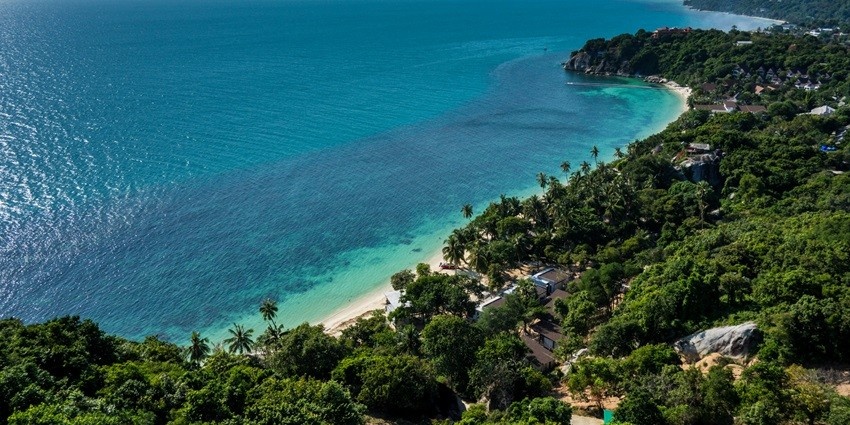 An aerial view of an island with trees and greenery beside an ocean in Pattaya
