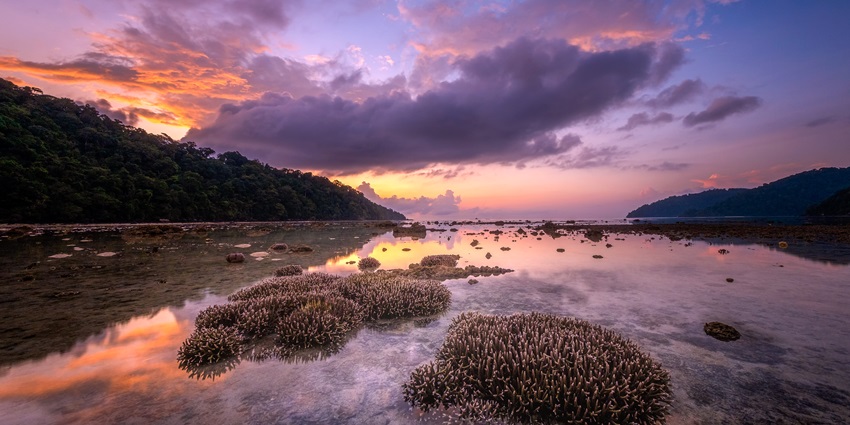 An evening shot of a beach that is very popular for scuba diving in Thailand with sky's reflection in water