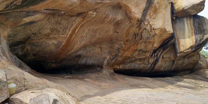 A cave system with a tall rocky hill over its narrow path to go in