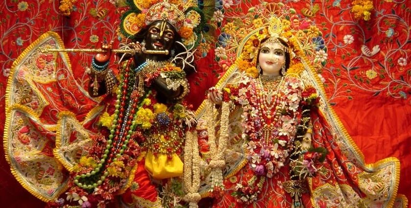 A picture of a temple's interior with the idols of Lord Krishna and Goddess Radha donned in luxury clothes