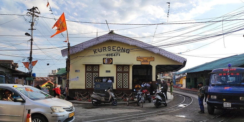 Darjeeling Himalayan Railway station at Kurseong with toy train and hillside view.