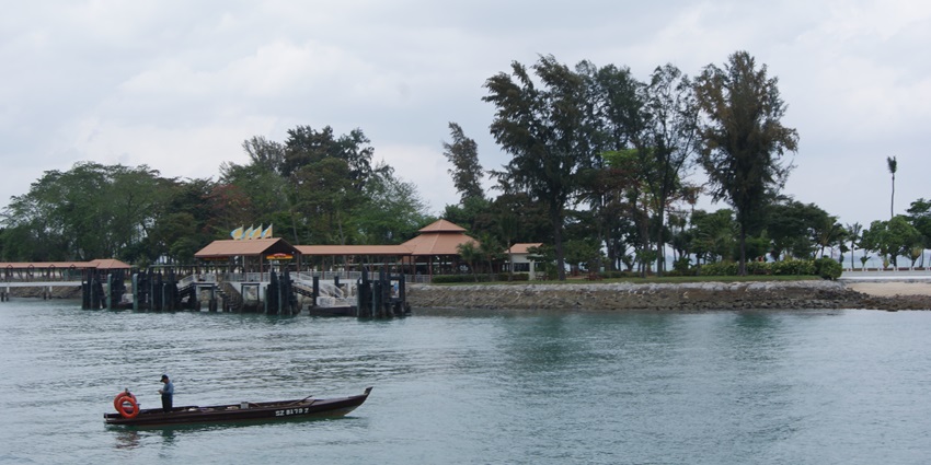 Panoramic view of Kusu Island featuring turquoise waters and lush, tropical greenery.