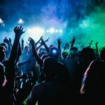 A breathtaking view of a group of people dancing in a nightclub under green lights.