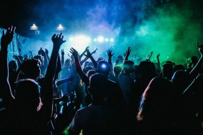 A breathtaking view of a group of people dancing in a nightclub under green lights.