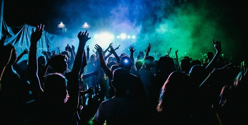 A breathtaking view of a group of people dancing in a nightclub under green lights.