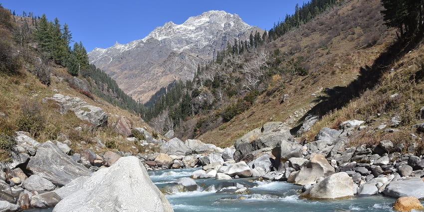 A picture of a tranquil river flowing through the majestic mountains of Himachal Pradesh