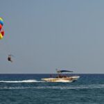 A picture showing the adventure sport of parasailing. People tied to a boat with a big parachute attached to their backs