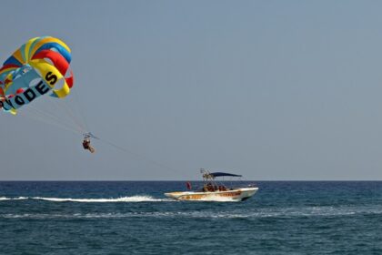 A picture showing the adventure sport of parasailing. People tied to a boat with a big parachute attached to their backs