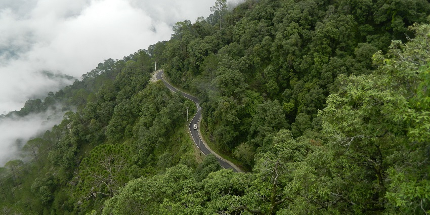 An aerial picture of a road that is enclosed by tall green mountains