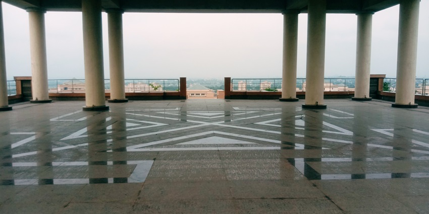 A picture of a meditation centre in Namsai with numerous pillars and a scenic view in front