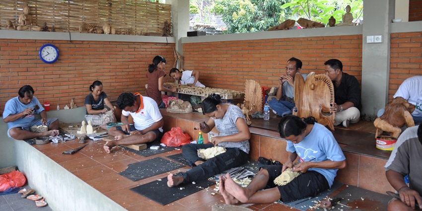 A picture of a wood carving centre with people using tools to carve wood into artefacts