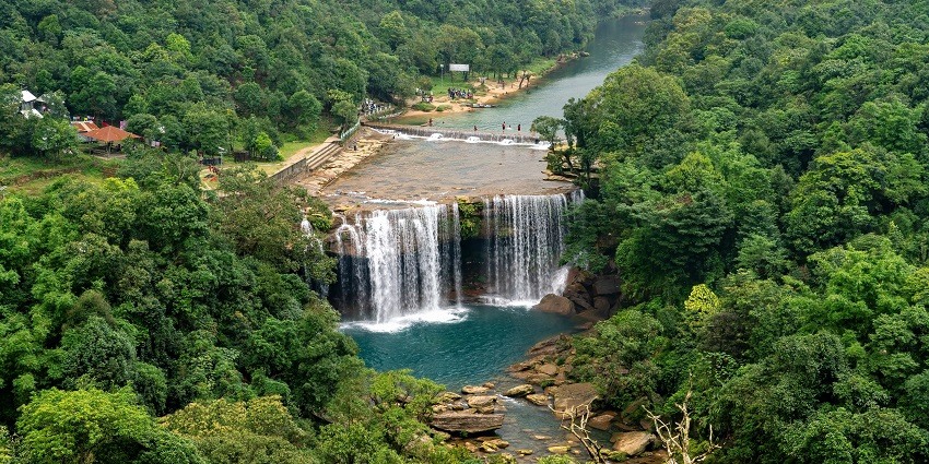 Scenic sight of the sparkling water descending down into the pool amidst a lush forest