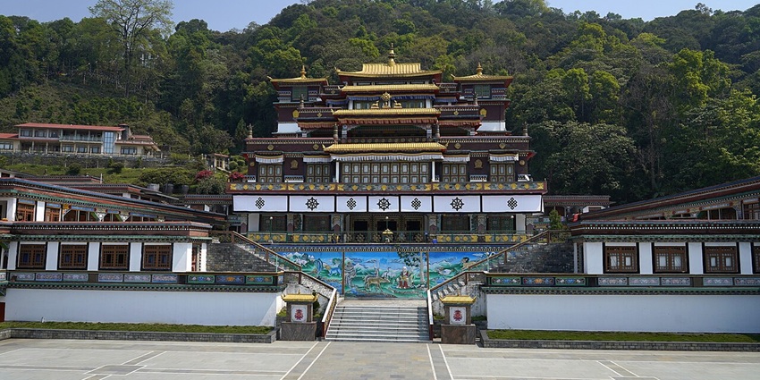 Tibetan monastery perched on forested slope, showcasing multi-tiered architecture