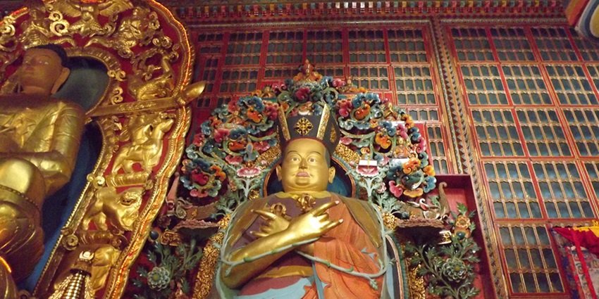 A view of a golden statue of the lord in a monastery with a stunning background.