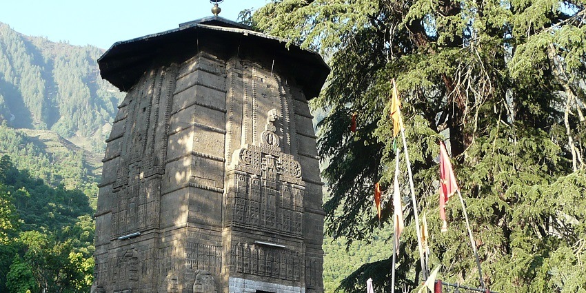 View of the famous Manimahesh Temple with lush greenery & mountains in the background.
