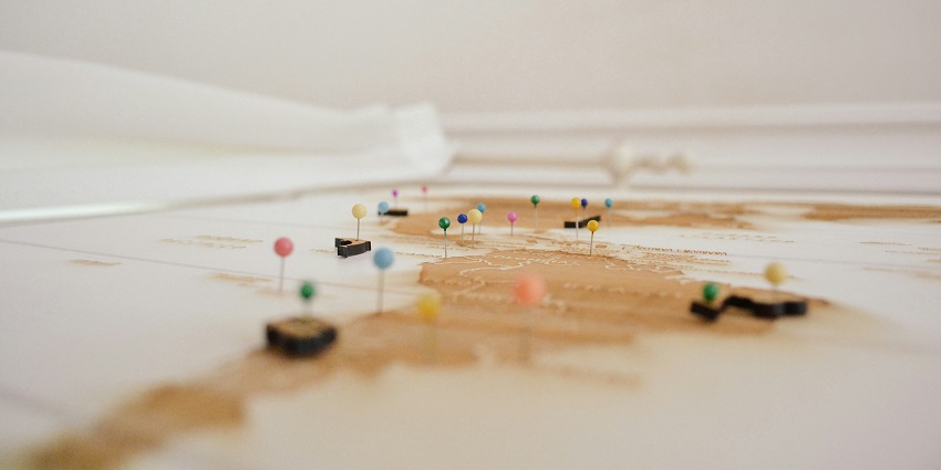 A focused view of colourful push pins on a map kept on a table during the daytime.