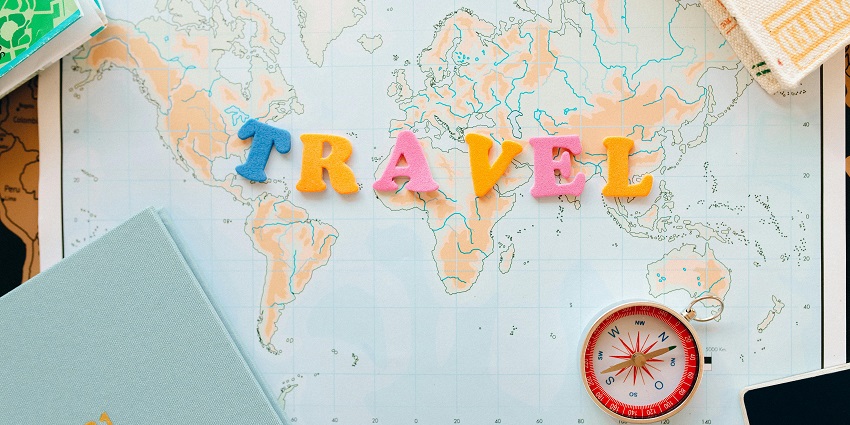 A stunning view of the world map with assorted alphabets saying travel from the above.