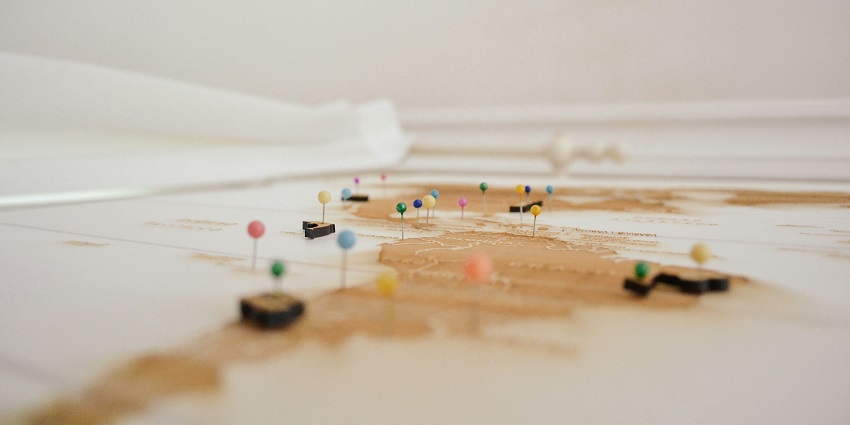 A selectively focused view of a map with assorted push pins on it on a flat surface.