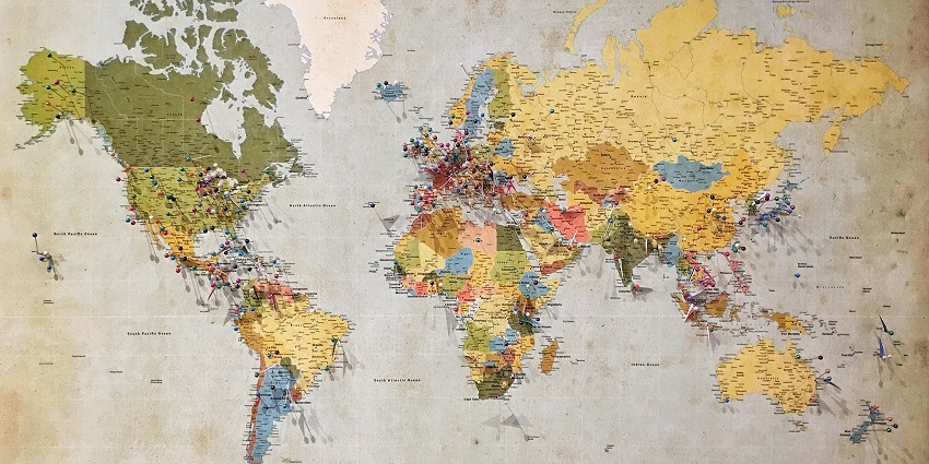 stunning frontal view of a colourful world map with assorted push pins on top of it.