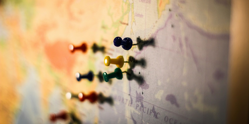 A view of a person’s finger on a blue, yellow and white map standing on a table.